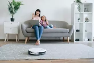 Cleaning robot doing job while owners having online talk