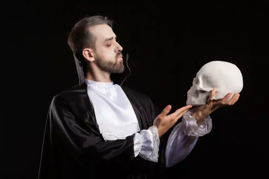 Man dressed in Dracula costume for halloween looking at a human skull