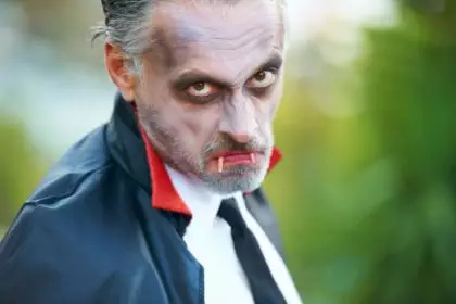 Mature man dressed up as Dracula for Halloween, scowling at the camera