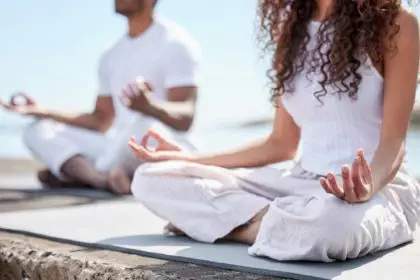 Mindful of mental health. Cropped shot of an unrecognizable couple practicing yoga at the beach.